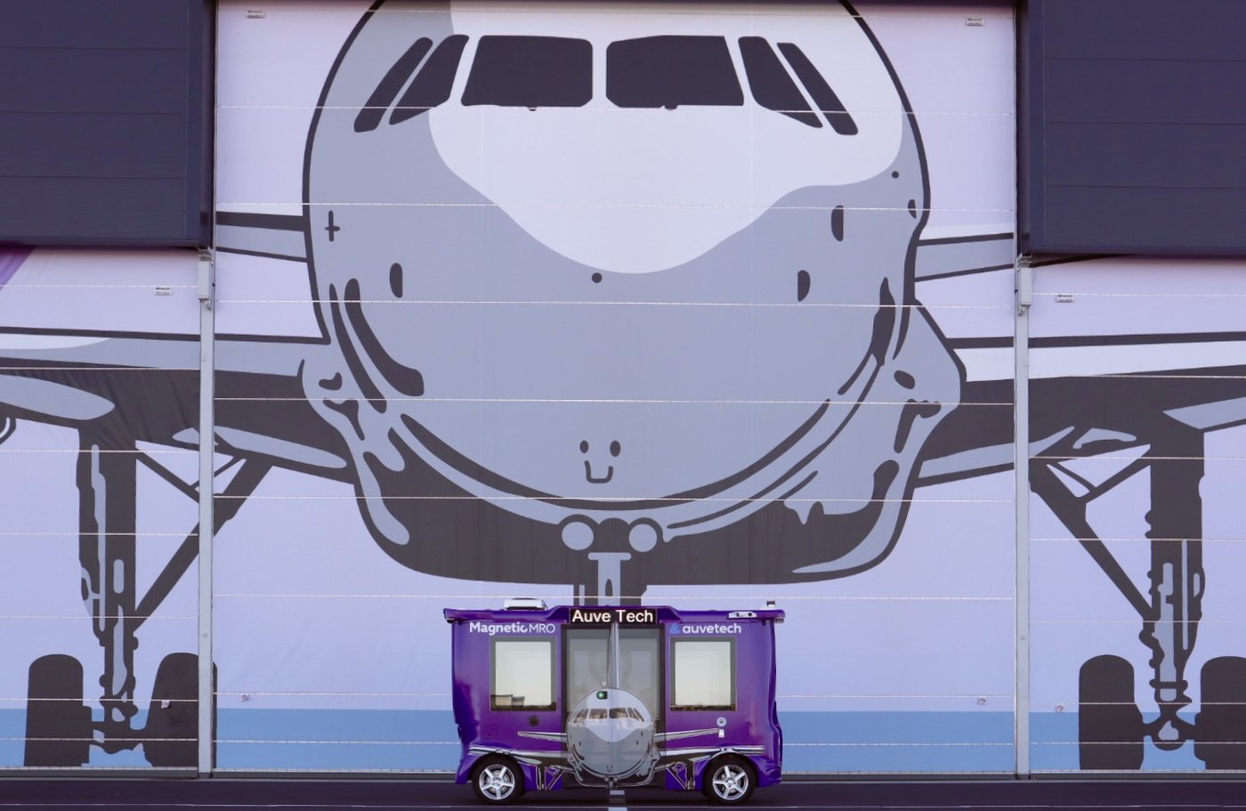 An Auve Tech MiCa shuttle parked in front of a Magnetic MRO hangar at Tallinn Airport.
