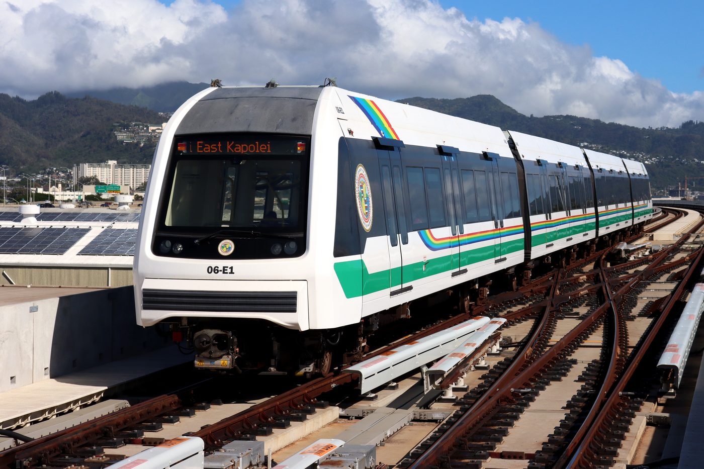 A Skyline train with a rainbow stripe and East Kapolei on its destination sign arrives at Ahua (Lagoon Drive) station in Honolulu in November 2025.