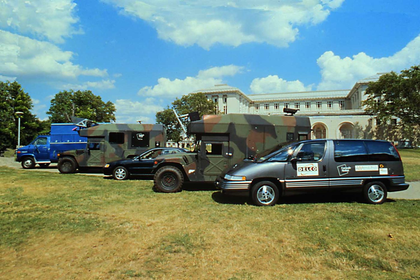 Carnegie Mellon's Navlab vehicles 1 through 5, with Navlab 5, a grey Pontiac minivan with Delco livery, in front.