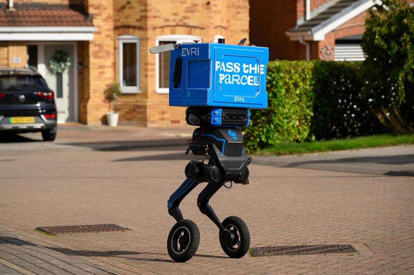 The two-legged delivery robot that Evri is trialing with Refined Robotics, carrying an Evri parcel box on a residential street.