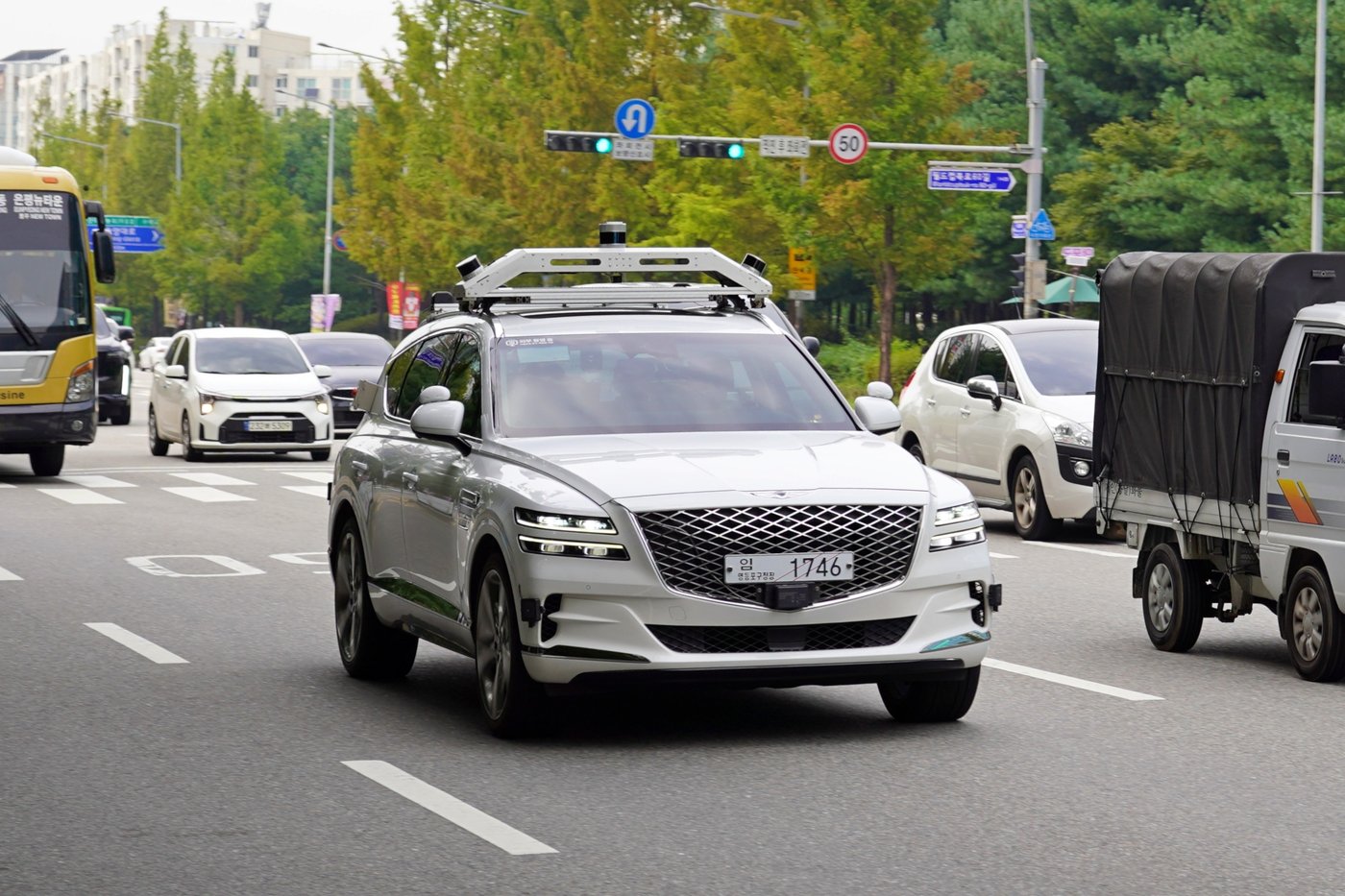 A RideFlux autonomous Genesis GV80 with a roof-mounted sensor rack drives on a city street in South Korea. Company photo.