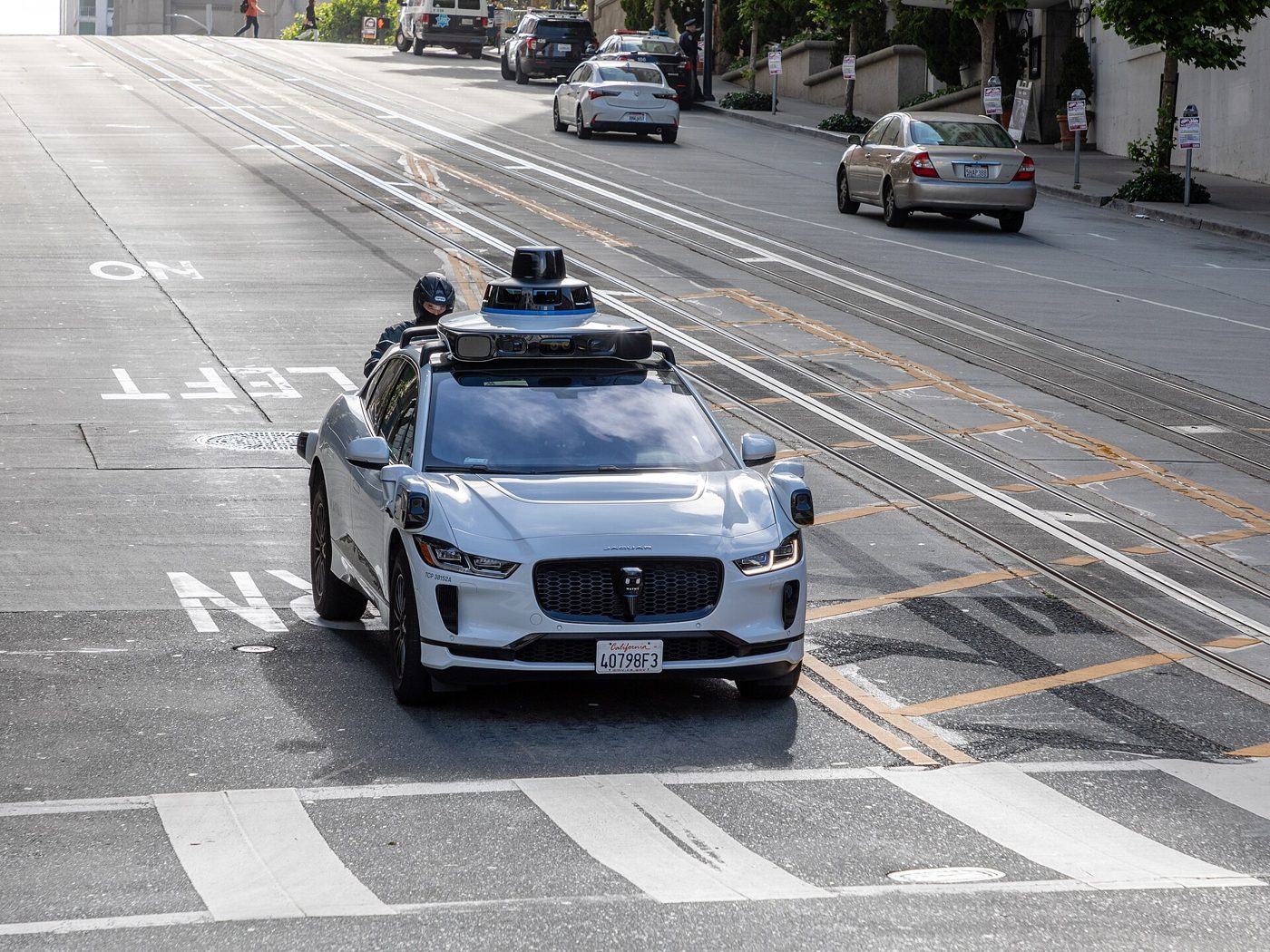 A Waymo Jaguar I-Pace robotaxi crosses the cable car tracks on California Street in San Francisco.