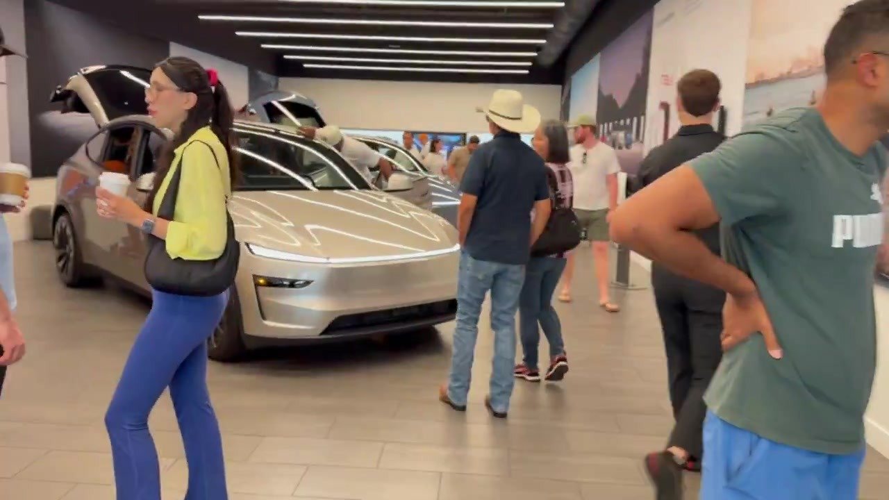 Visitors look at a Tesla Cybercab on a showroom floor.