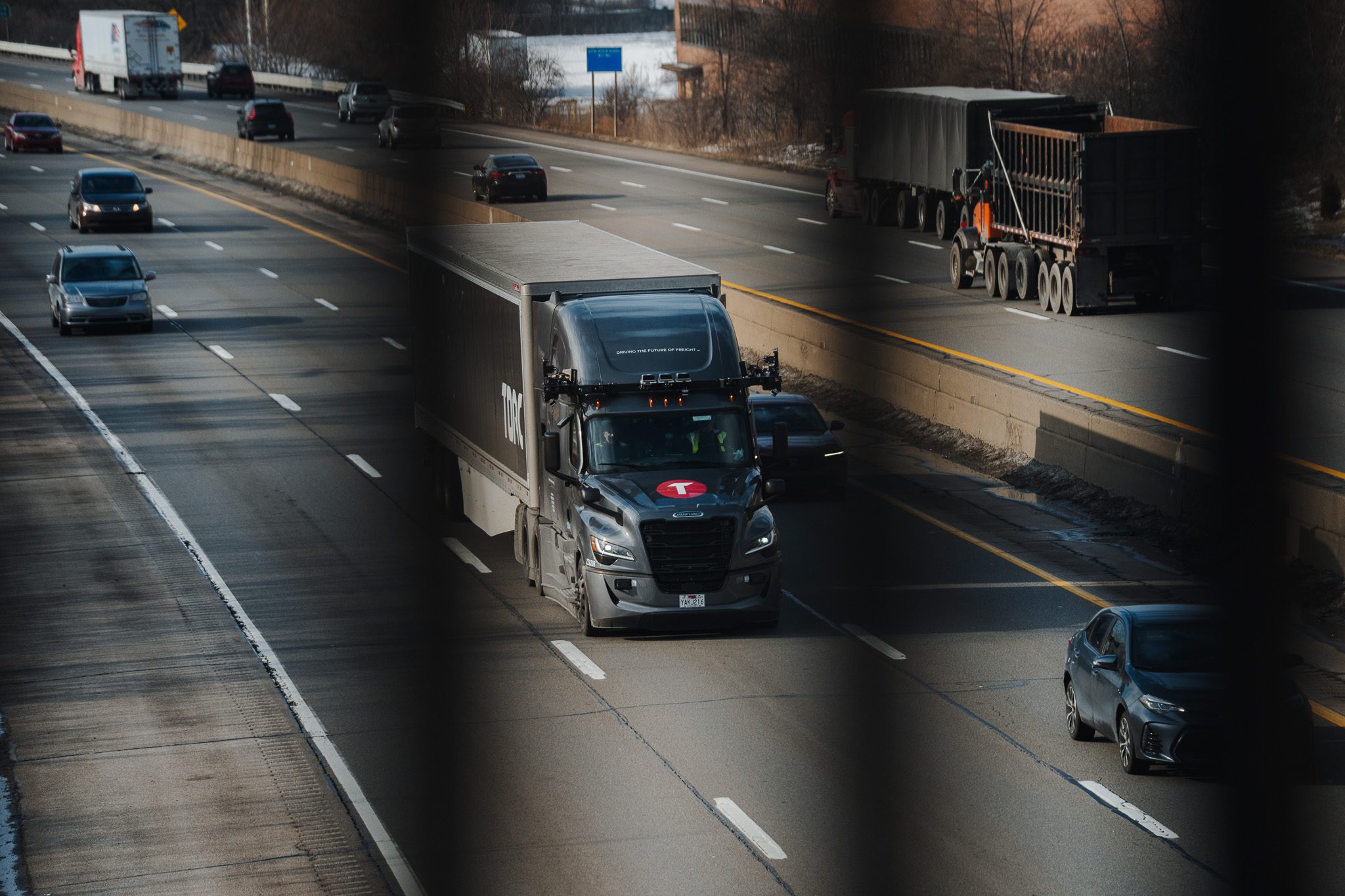 A Torc Freightliner with roof sensors in mixed highway traffic.