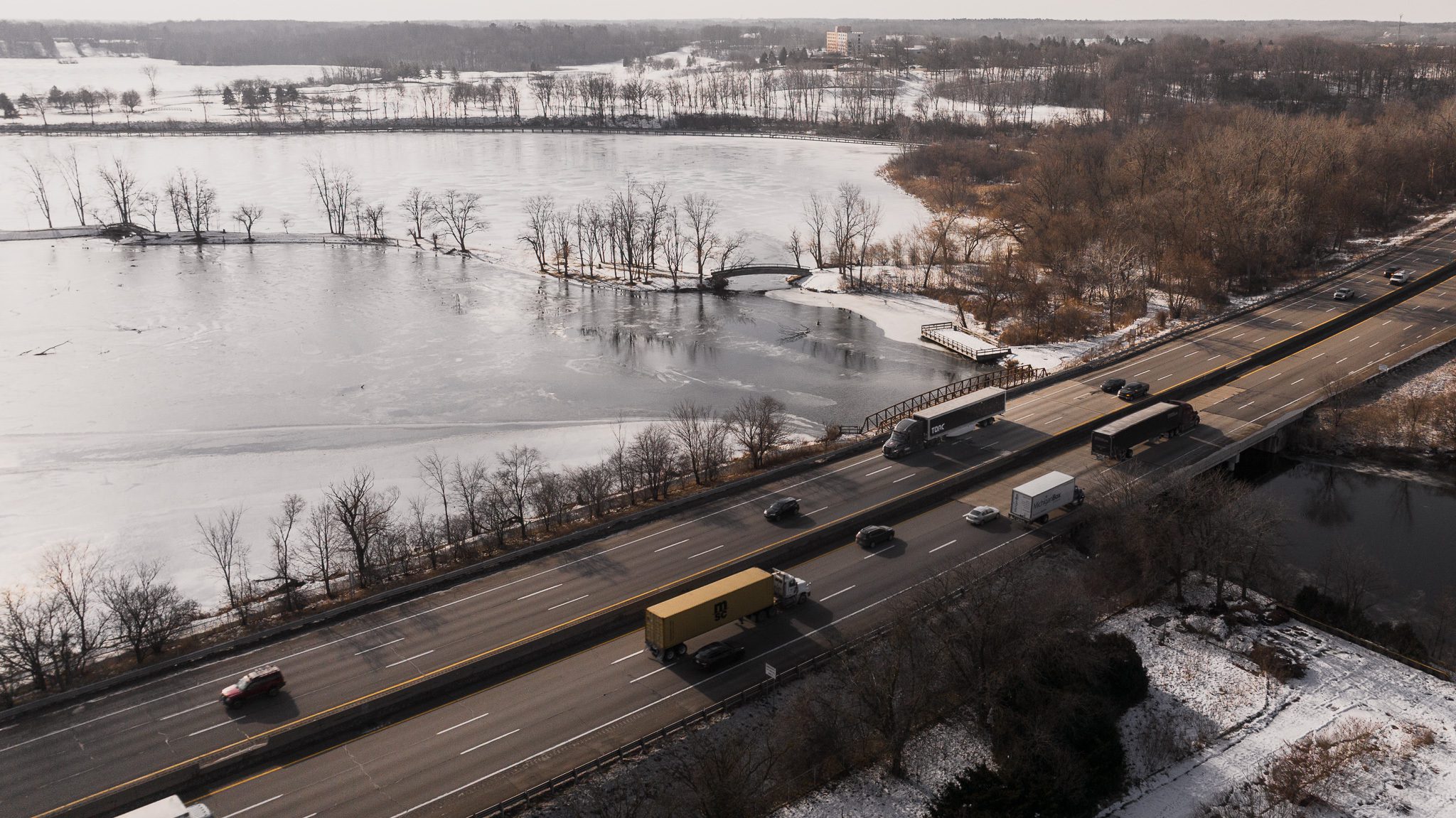 Torc and other trucks on a winter highway beside frozen water.