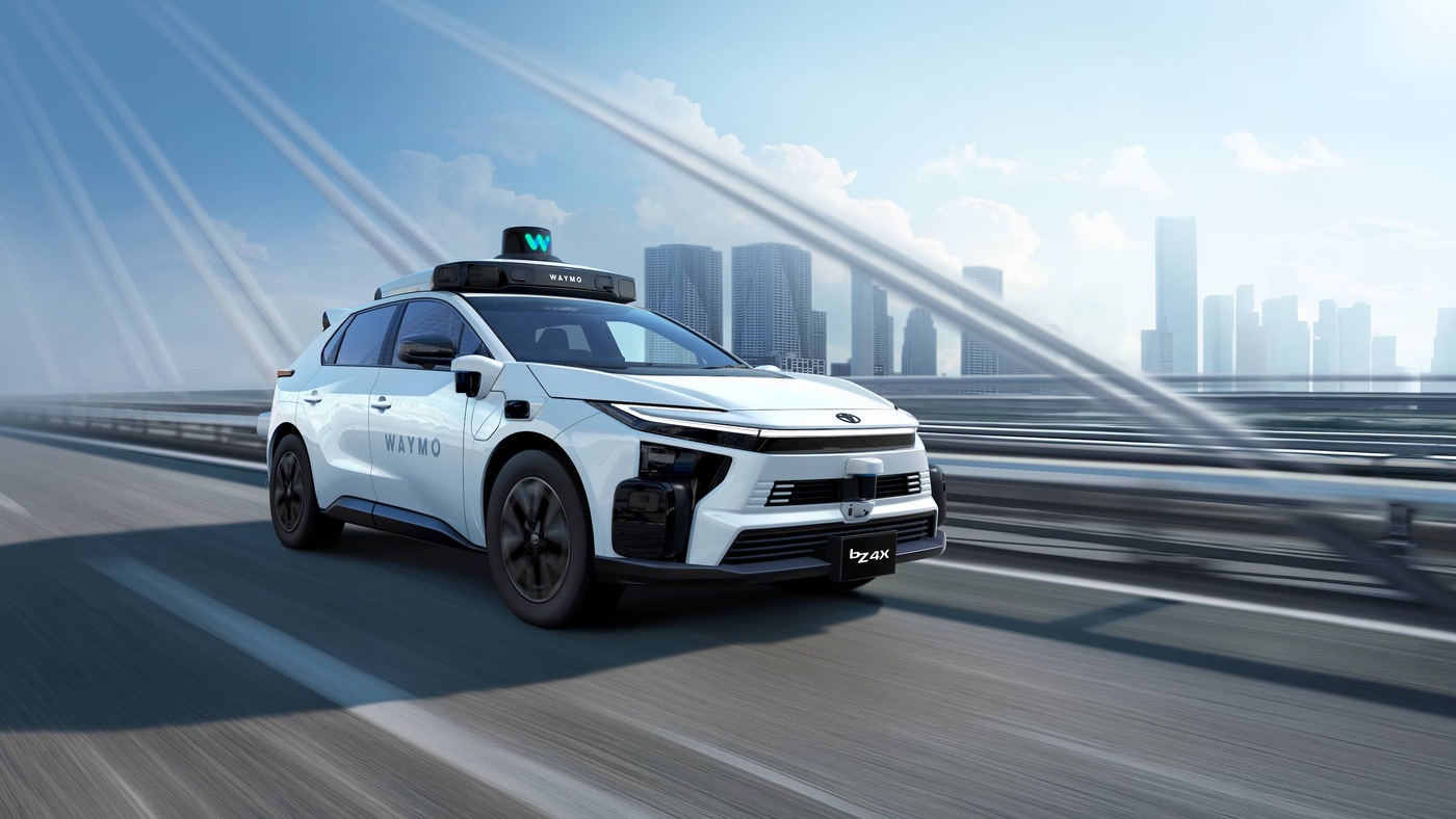 A white Toyota bZ4X carrying Waymo's roof sensors and Waymo lettering, in a press image released by Waymo and Toyota.