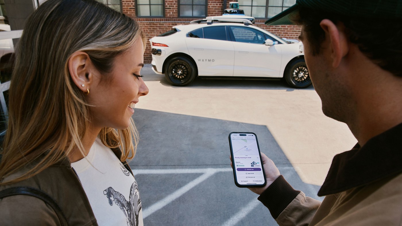 Riders check the Lyft app beside a Waymo vehicle in an image Lyft released for the Nashville launch.