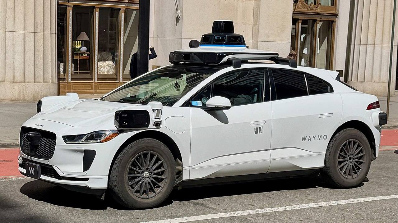 A Waymo Jaguar I-PACE on a city street, illustrative U.S. scene.